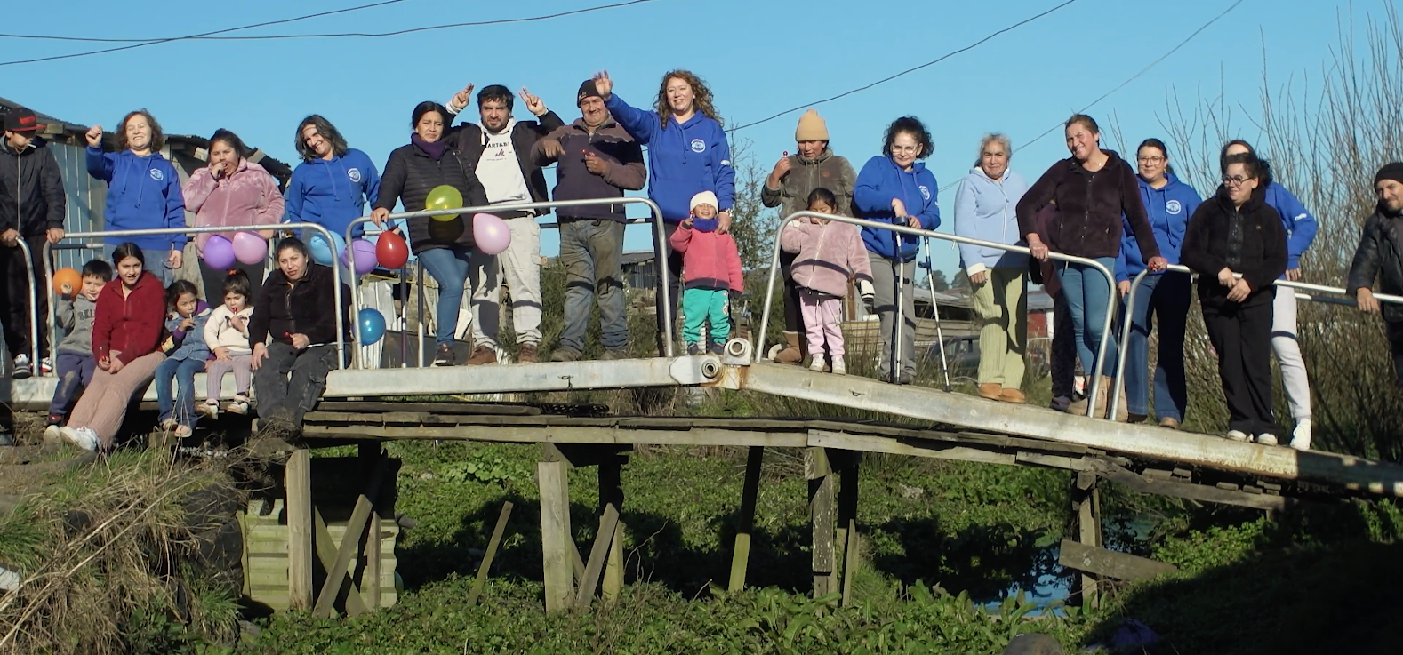 Vecinos y voluntarios reunidos sobre una pasarela de Nuevo Amanecer