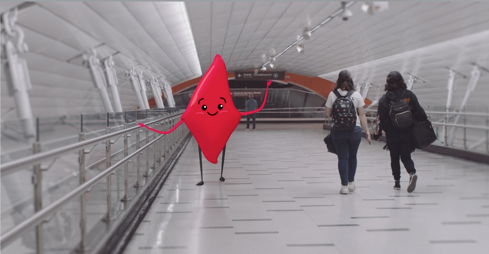 Personaje rojo integrado en el pasillo de una estación de Metro, junto a pasajeros