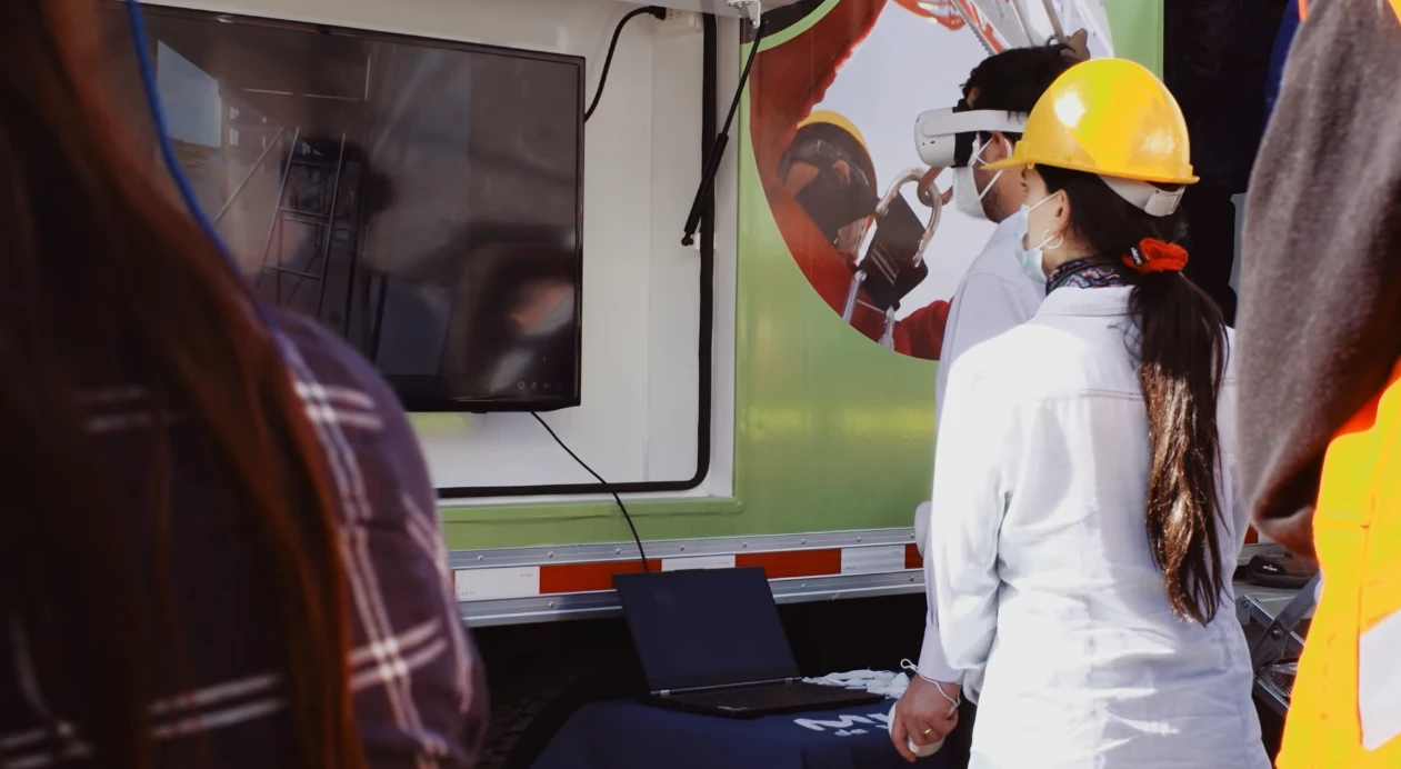 Participante con casco utiliza realidad virtual junto a una pantalla de monitoreo y la unidad móvil