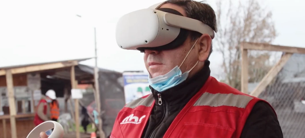 Trabajador con chaleco rojo utiliza un visor de realidad virtual en terreno